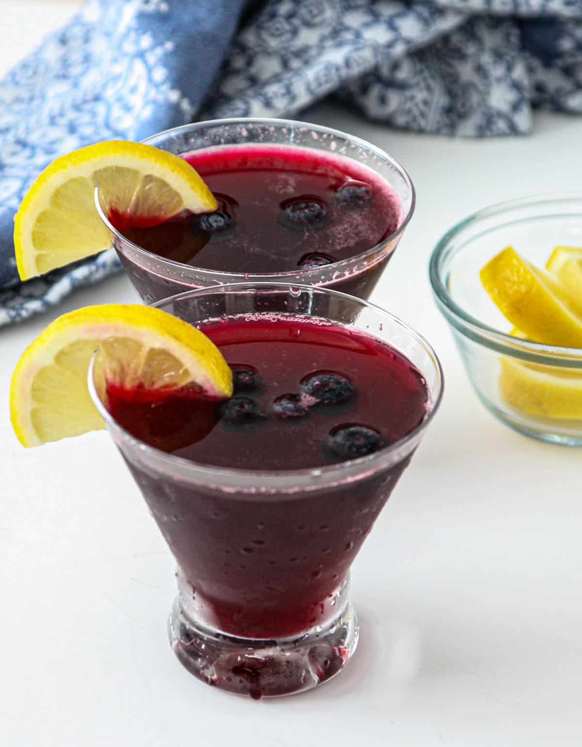 Two blueberry martinis in stemless glasses.