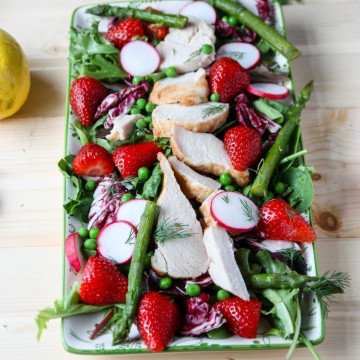 A platter of salad with chicken on a table